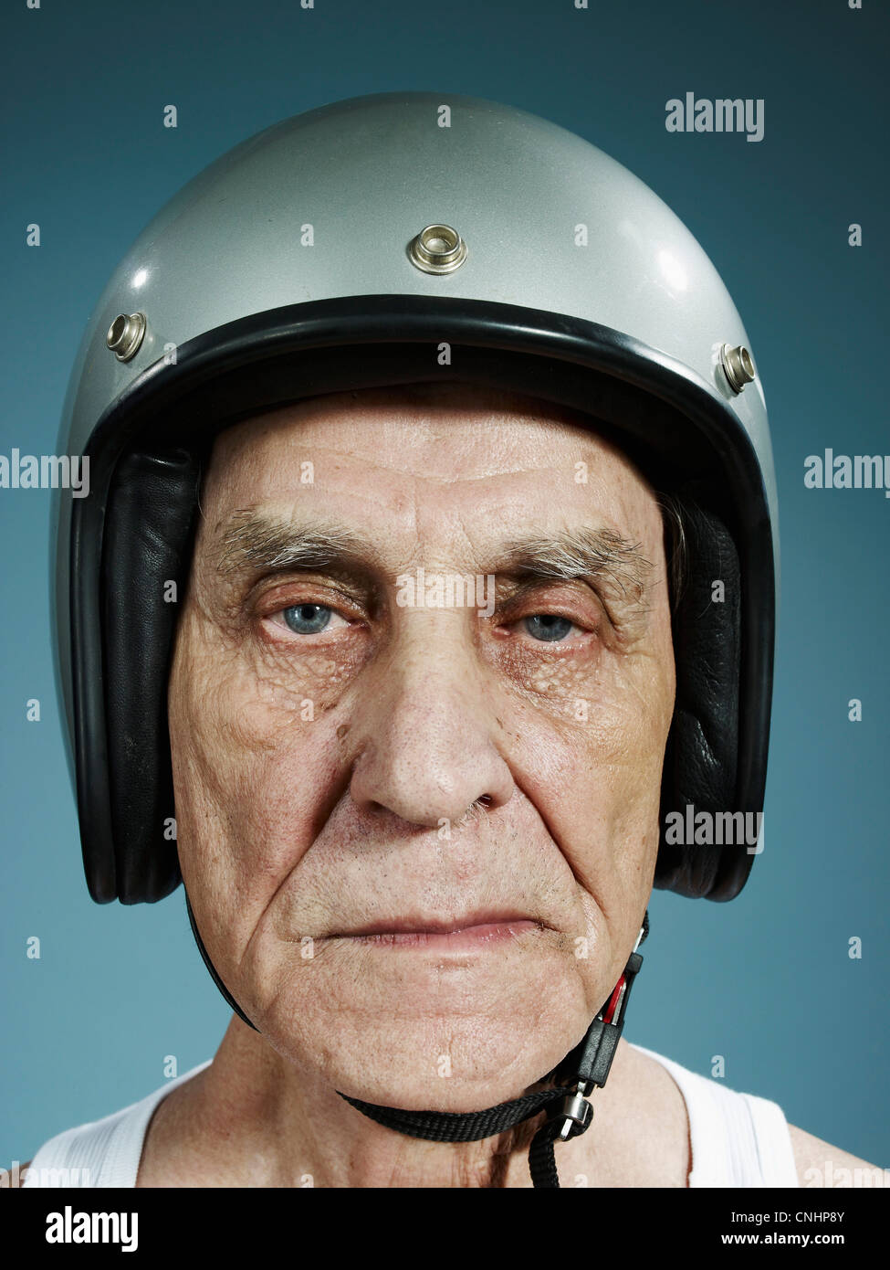 A headshot of a frowning senior man wearing a crash helmet Stock Photo