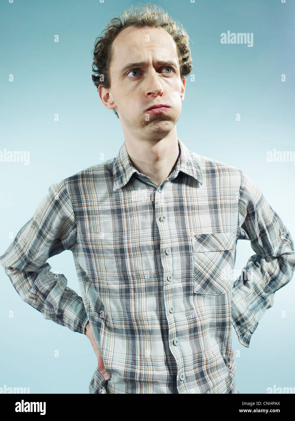 A man with puffed cheeks looking away with uncertainty Stock Photo