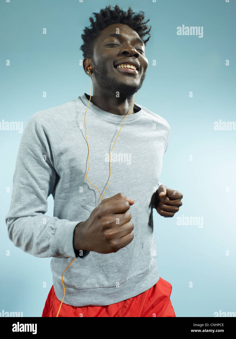 A young man wearing earbuds and running Stock Photo