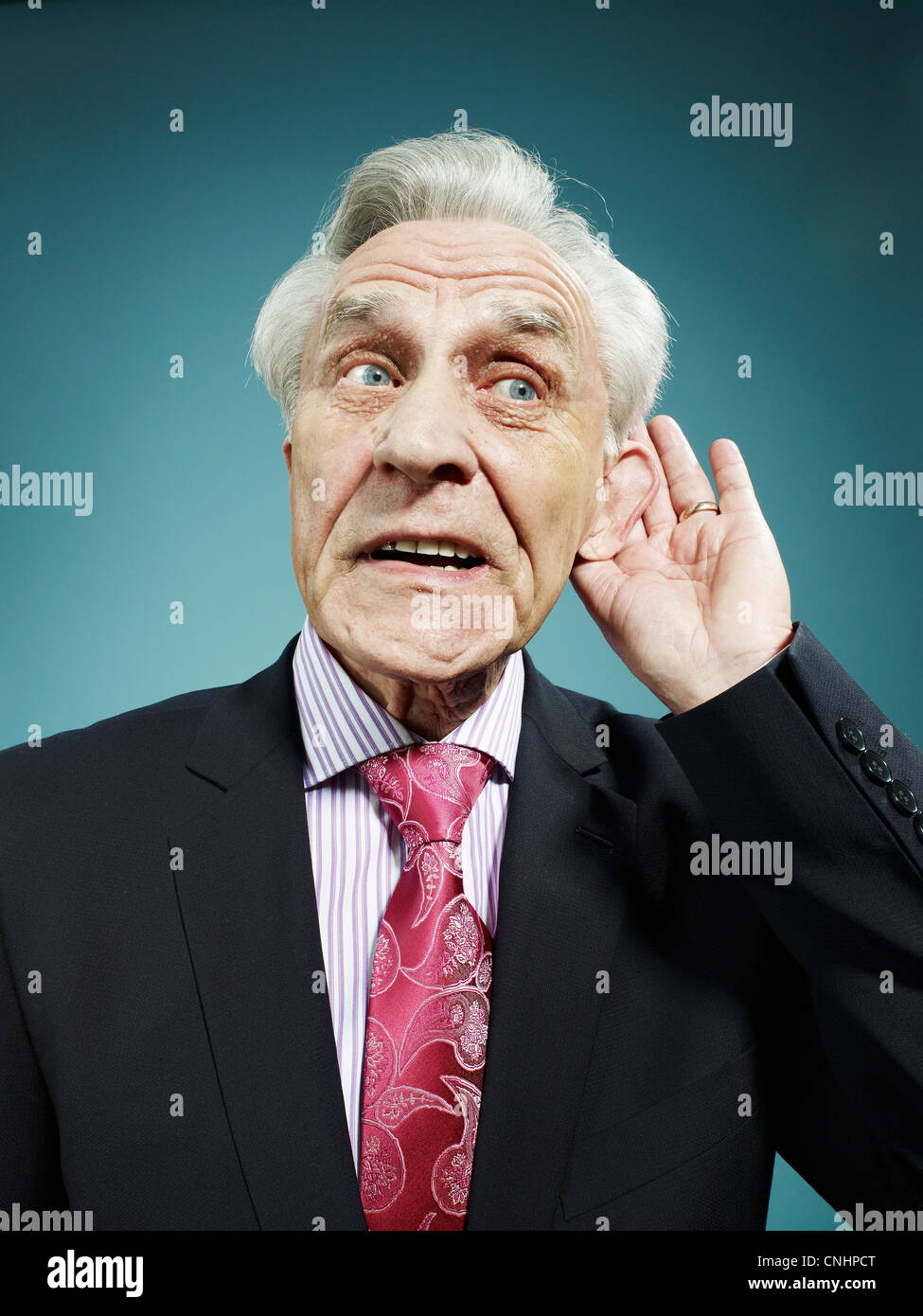 A senior man with his hand behind his ear Stock Photo