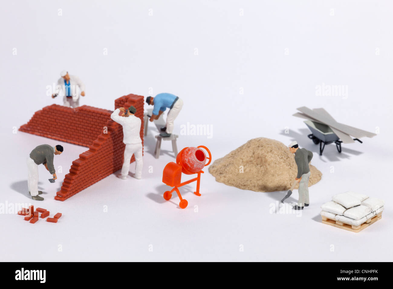 Miniature bricklayers building a brick wall Stock Photo