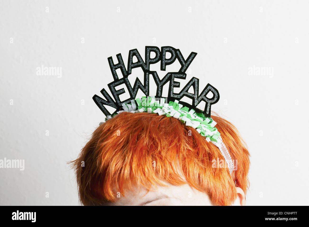 A woman wearing a party tiara with Happy New Year on it, top of head Stock Photo