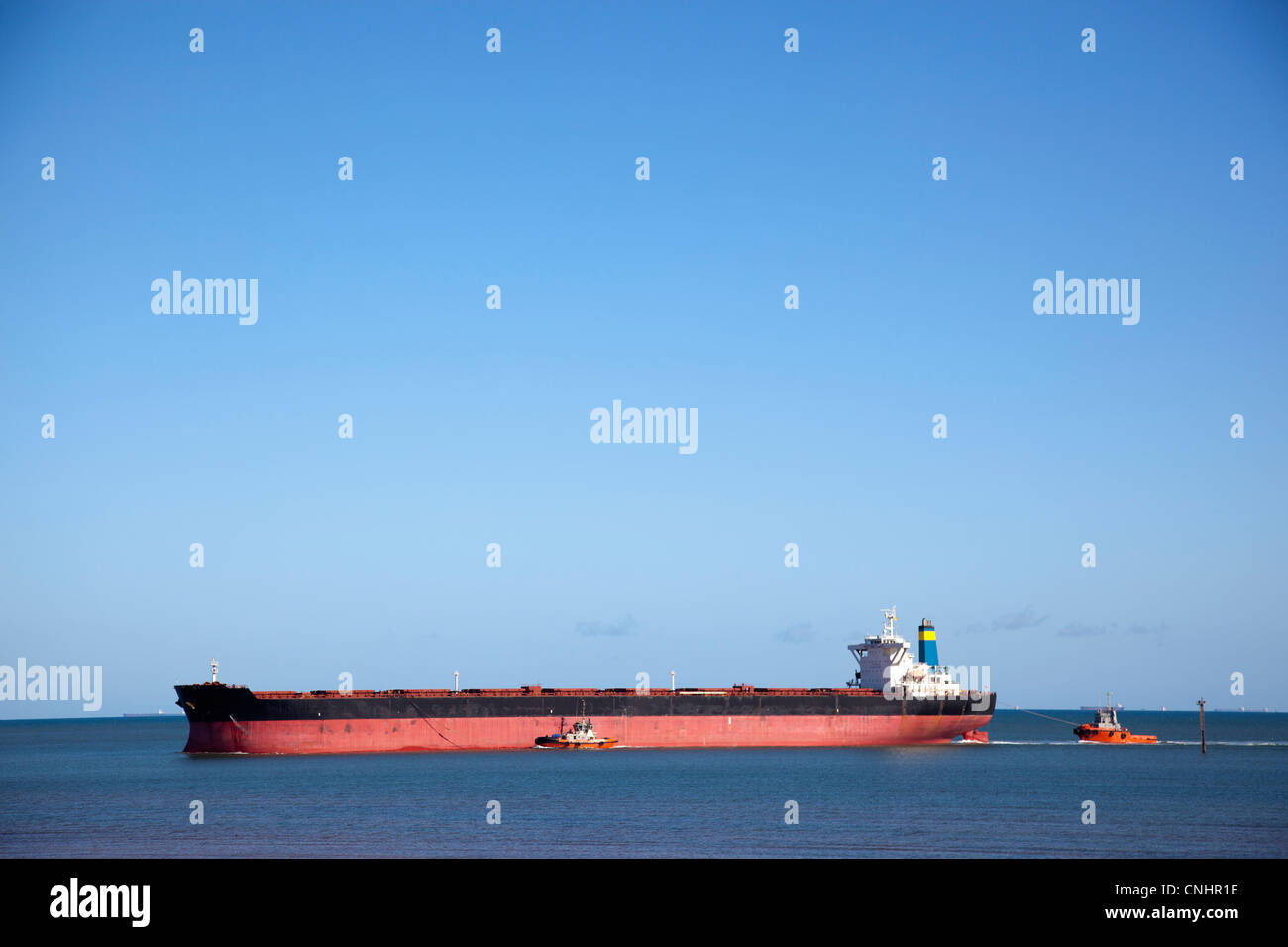 A tugboat pulling a freight ship Stock Photo