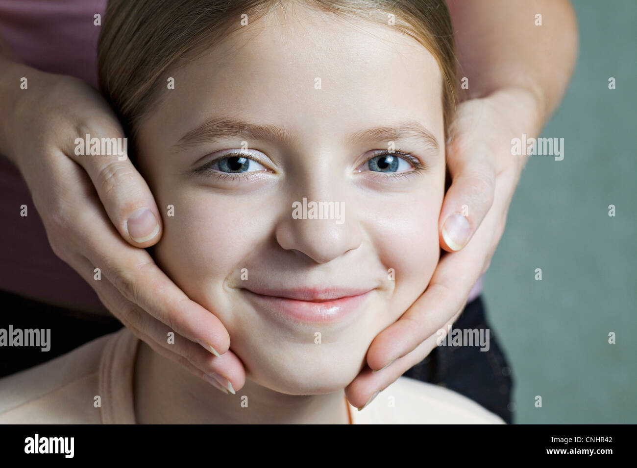 Portrait of daughter with Mother's hands on her cheeks Stock Photo
