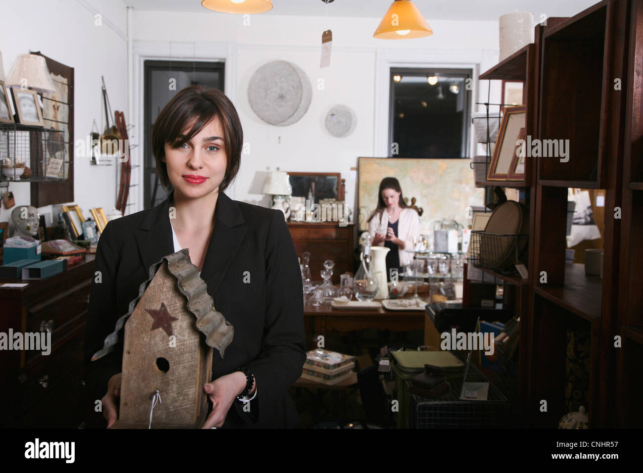 A woman holding an old birdhouse in an antiques shop Stock Photo