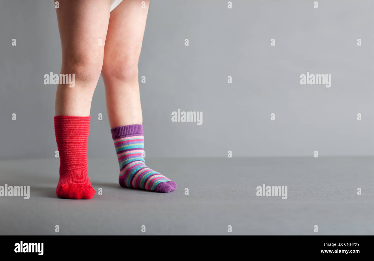 Child wearing one red sock and one striped sock Stock Photo Alamy