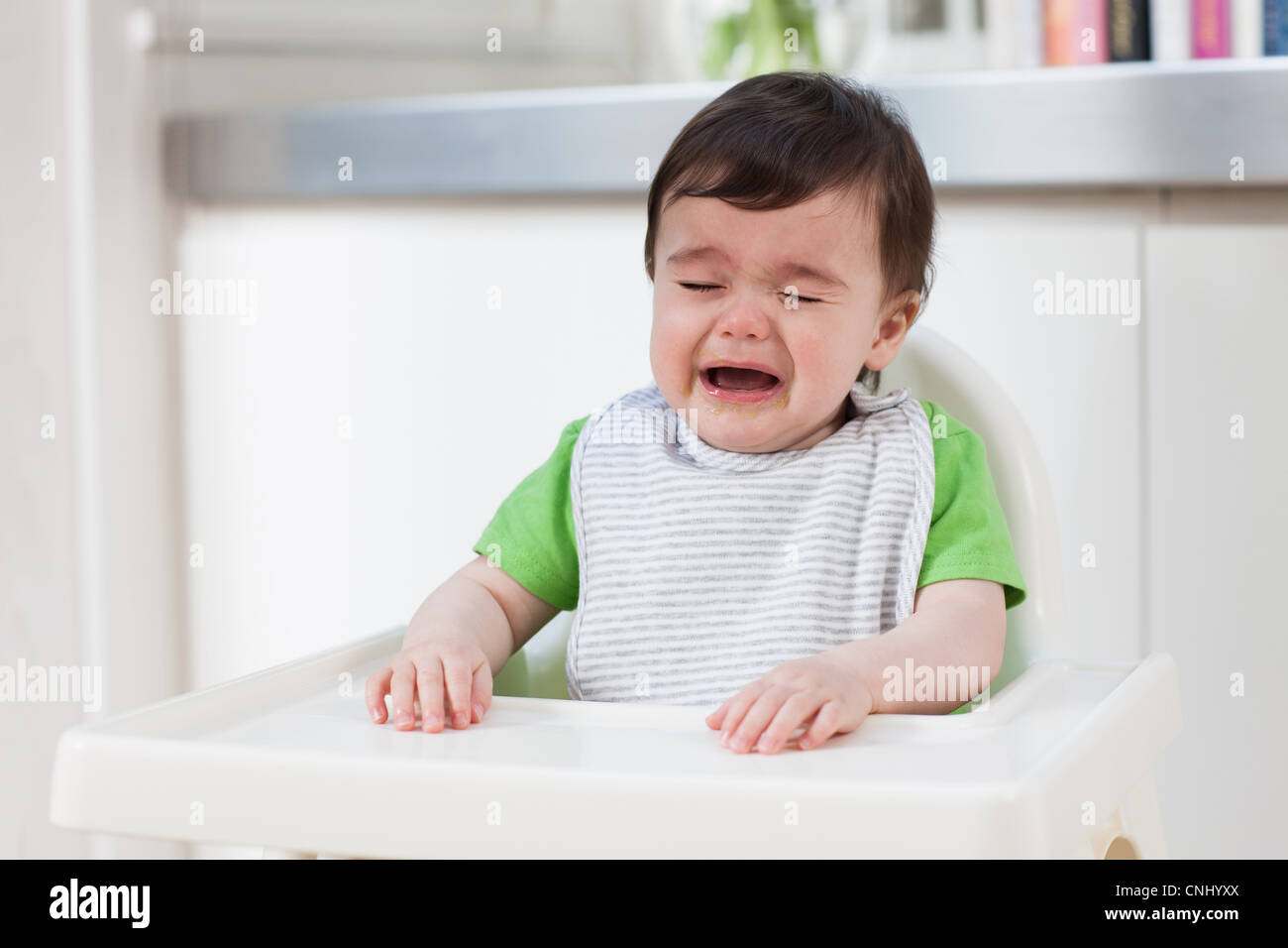 Baby boy in high chair, crying Stock Photo Alamy