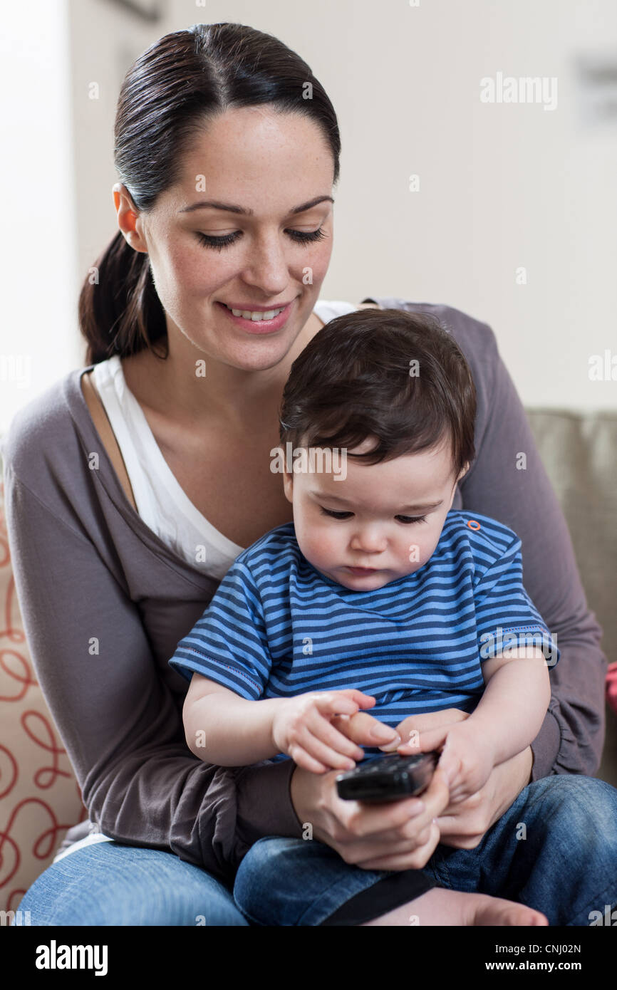 Mother and baby boy holding remote control Stock Photo Alamy