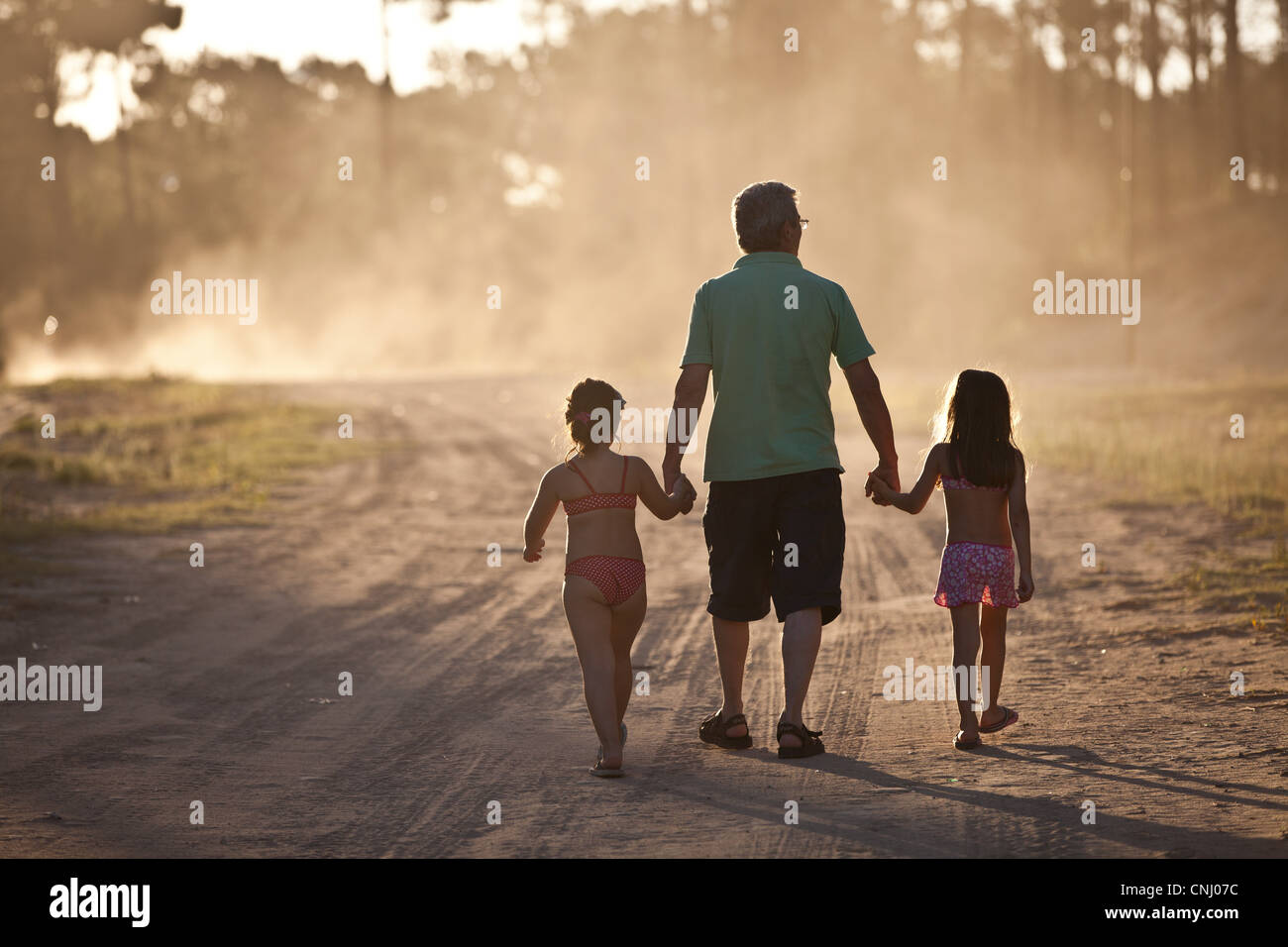 Father and daughters walking hand in hand on dust road Stock Photo - Alamy