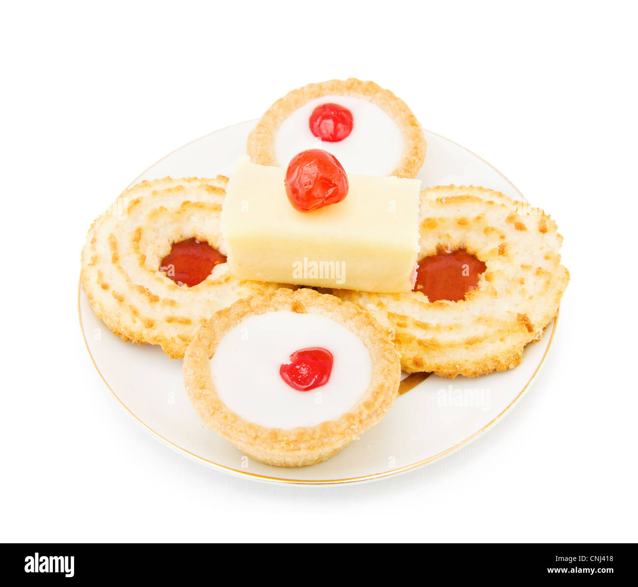 Coconut and jam biscuits with slice of cake and cherry on top. Isolated