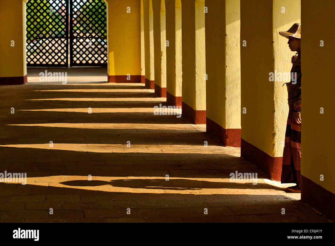 Columns, shadows and silhouettes. Woman standing in arch. Ananda temple, Pagan, Burma. Bagan, Myanmar. Model Released Stock Photo