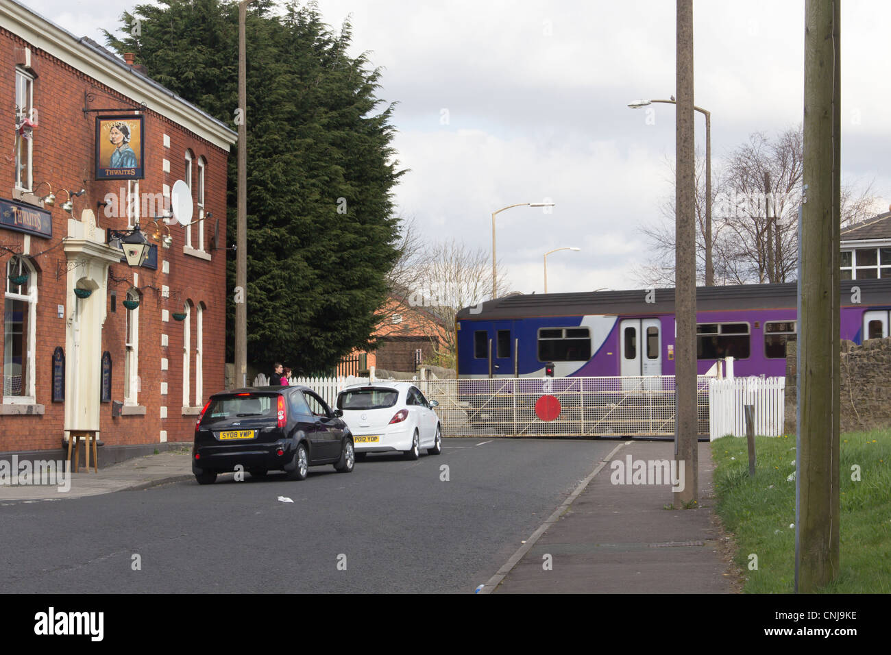 Traffic waiting for the passing train at the manually operated  railway level crossing at Daisyfield, Moss Street, Blackburn. Stock Photo