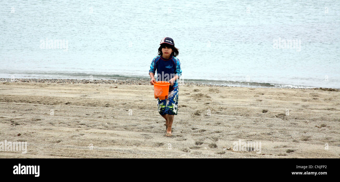 Boy walking with bucket on beach Stock Photo Alamy
