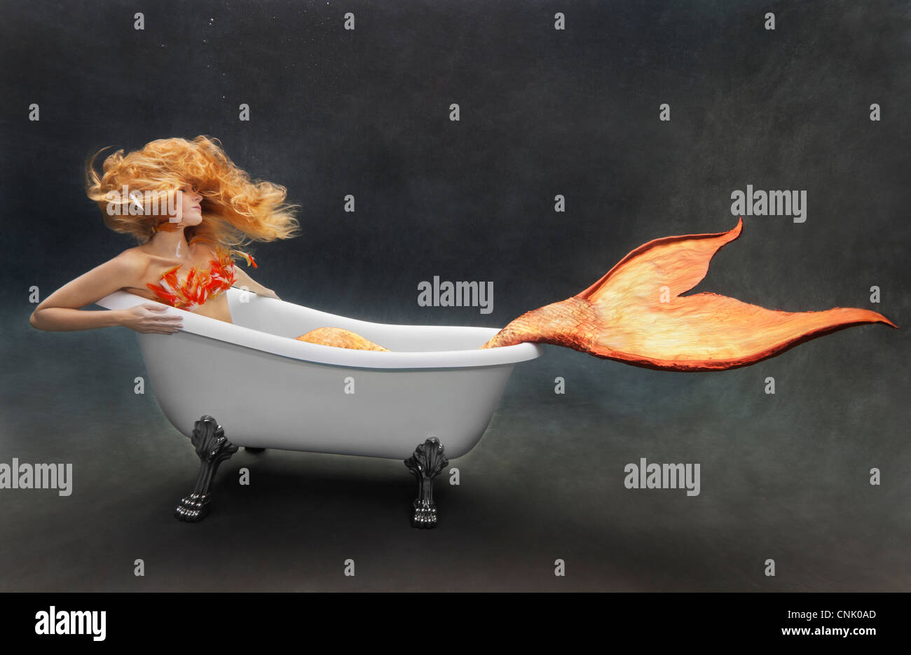 Young mermaid lounging underwater in her Victoria + Albert bathtub Stock Photo