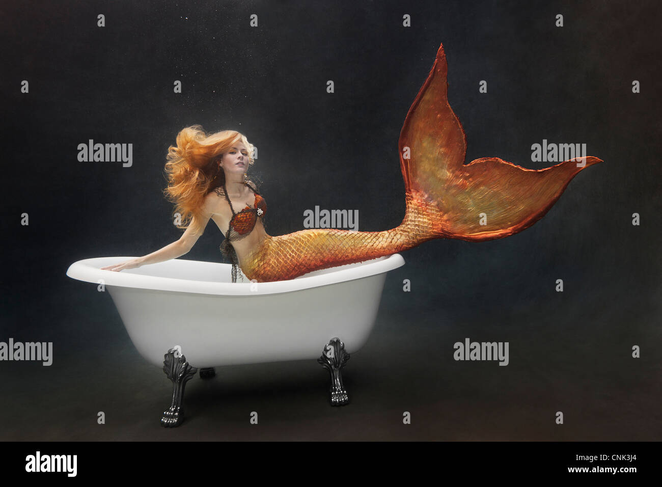 Mermaid underwater sitting on the edge of her Victoria + Albert bathtub Stock Photo