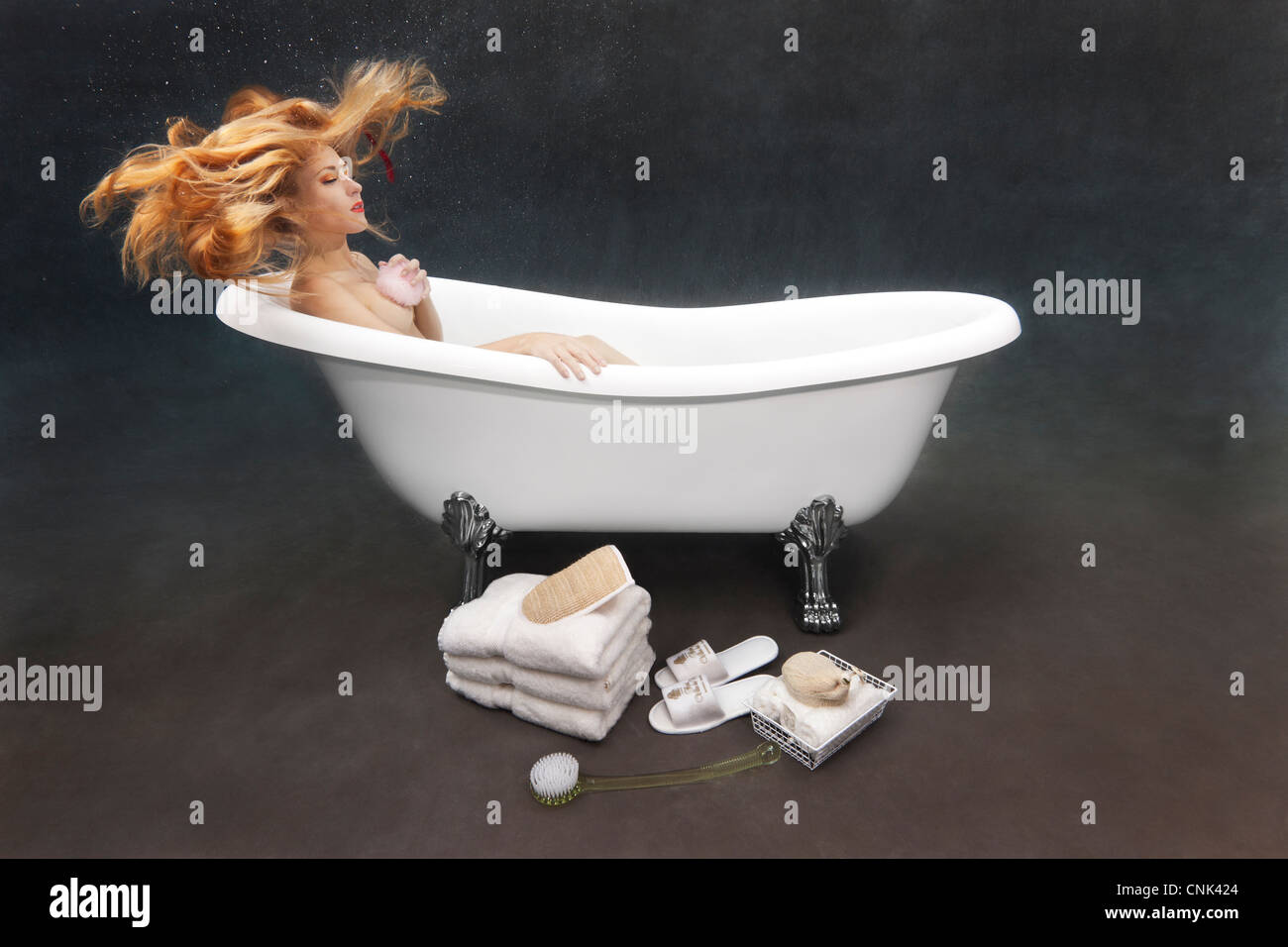 Young woman bathing herself underwater in her Victoria + Albert clawfoot bathtub Stock Photo