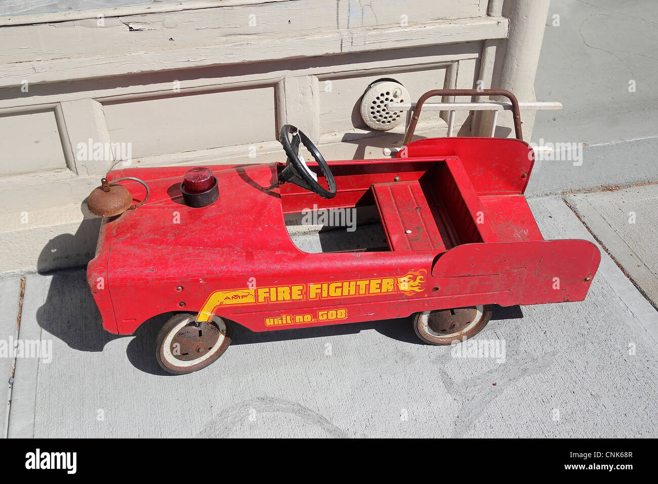 An old toy firetruck on a sidewalk in front of a store in Newport, Rhode Island Stock Photo