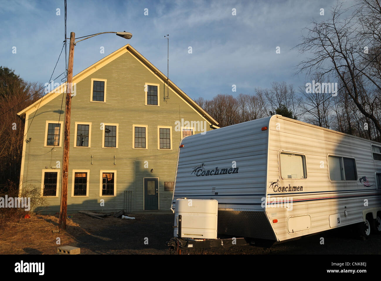 A trailer and a building in the small Western Massachusetts town of Colrain, lit by the late afternoon sunlight. Stock Photo