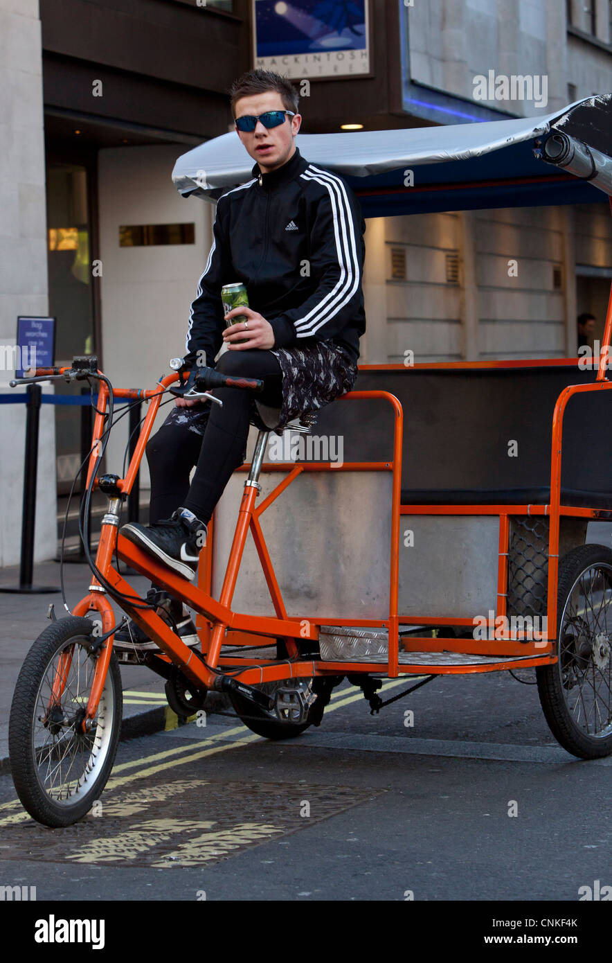 The Rickshaw Rider Full length portrait of a rickshaw rider taking a break, London ...