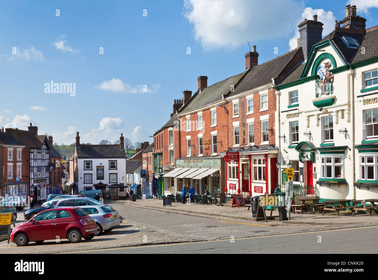 Town centre shops and parked cars in the Market Place Ashbourne Derbyshire England UK GB EU Europe Stock Photo