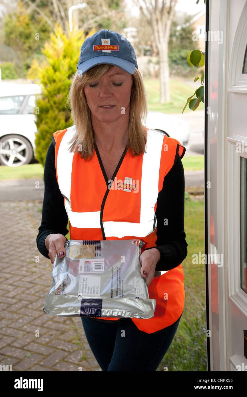 Royal Mail female post woman delivering a special delivery packet Stock