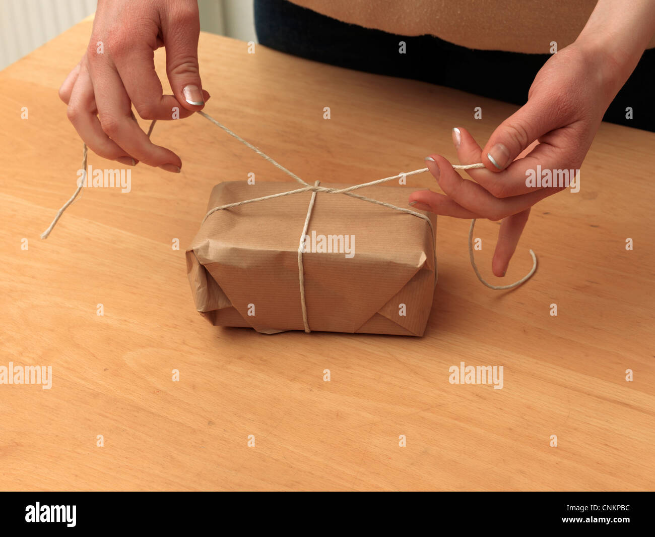 Tying Knot In String Around A Parcel Stock Photo - Alamy