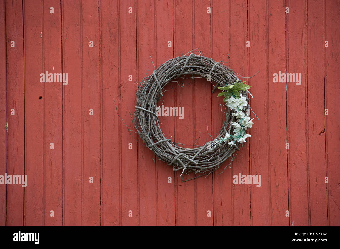 Grapevine wreath decoration hanging on a red barn door. Stock Photo