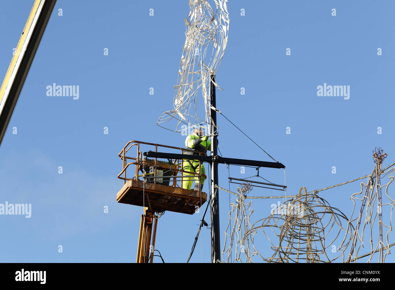 Workman using a crane and hoist to remove Christmas lights and decorations, UK Stock Photo