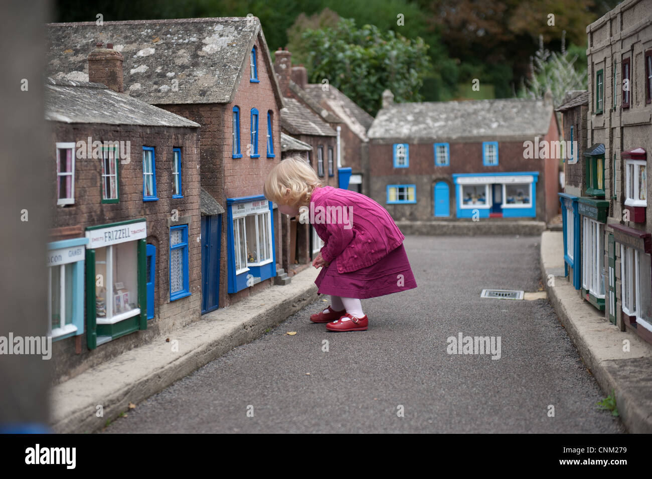 A little girl wanders around the streets of Wimborne Model Village in Wimborne, Dorset Stock Photo
