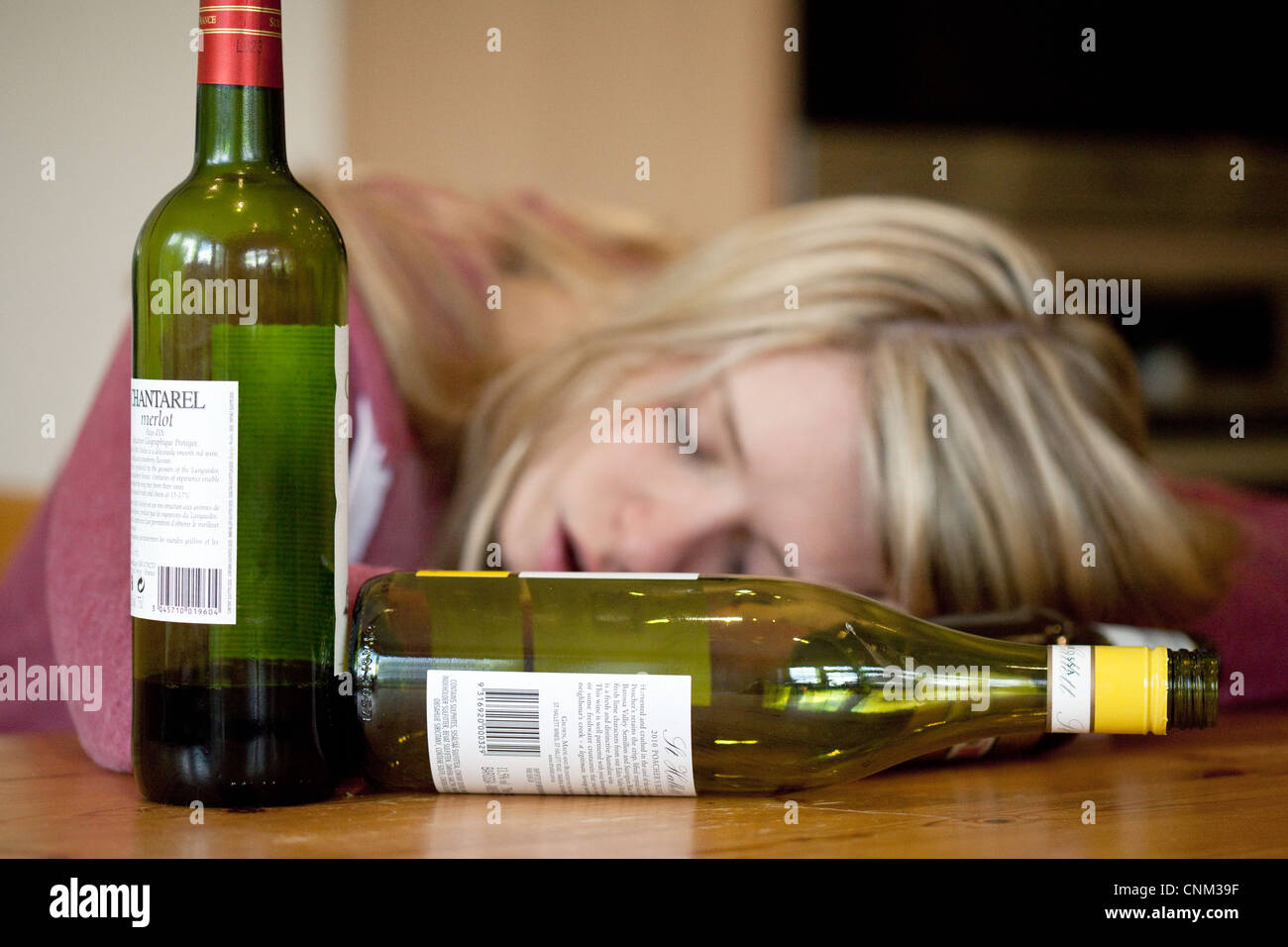 Young blonde alcoholic drunk woman, with empty bottles of alcohol, UK - Posed by a Model Stock Photo