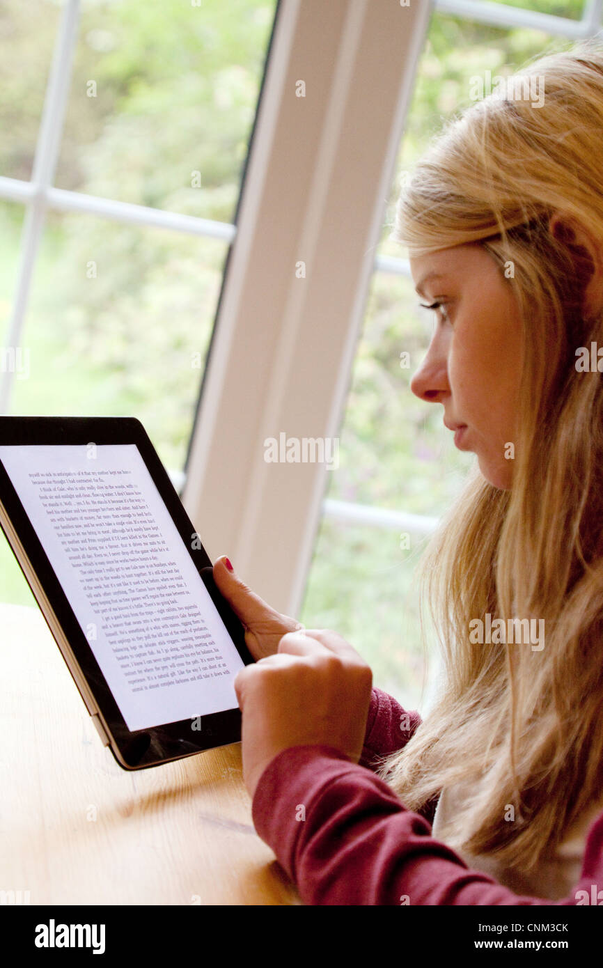 Blonde teen teenage girl reading an ebook on an iPad inside indoors