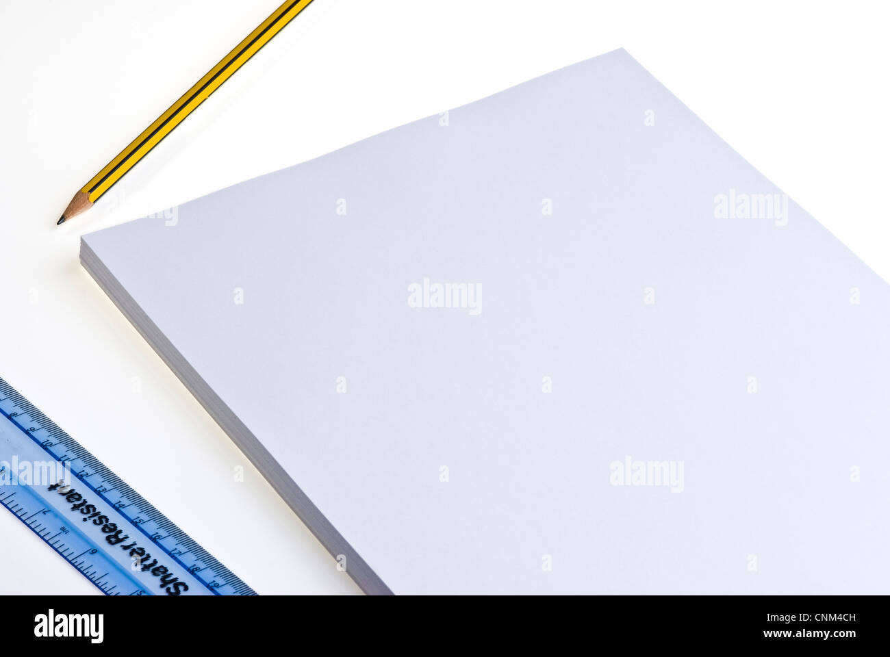 Blank pad of white paper with a pencil and plastic ruler, on a white ...