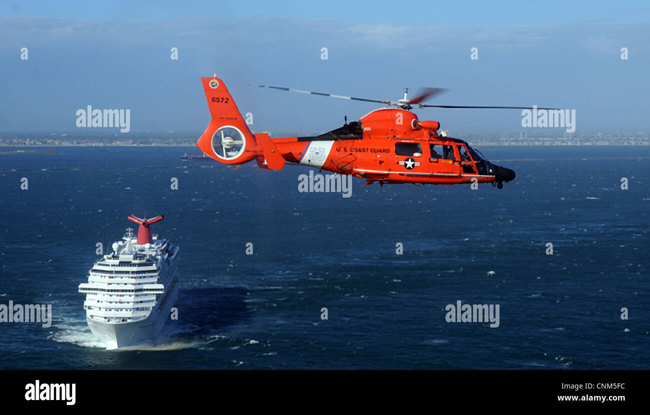 US Coast Guard Dolphin helicopter passes an incoming cruise ship during routine patrol March 18, 2012 off the coast of San Pedro, CA. The Port of Los Angeles' World Cruise Center is one of the largest cruise ship terminals in the United States. Stock Photo