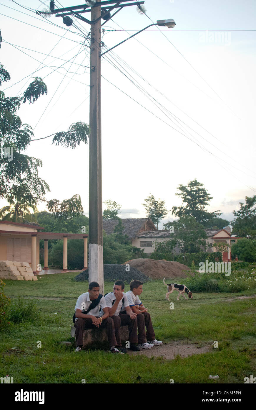 3 Cuban boys are waiting for a bus to school at dusk Stock Photo