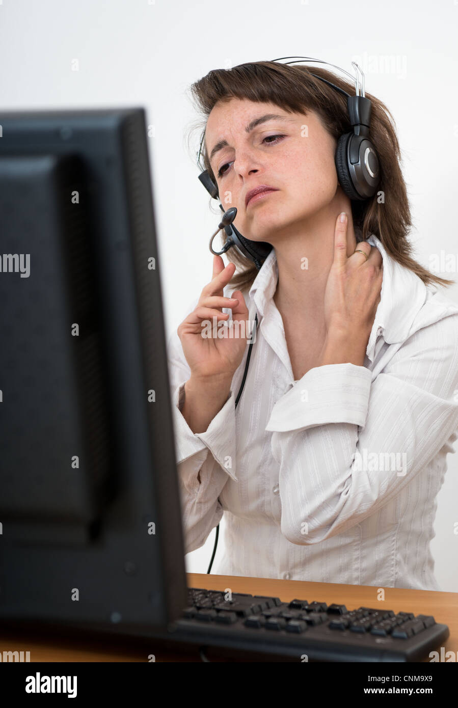 Young business person with neck pain working at computer Stock Photo