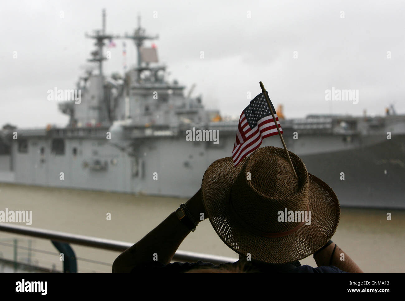 A woman looks through binoculars as the multipurpose amphibious assault ship USS Wasp (LHD 1) arrives for The War of 1812 Bicentennial Commemoration in New Orleans. The event is part of a series of city visits by the Navy, Coast Guard, Marine Corps and Operation Sail beginning in April 2012 and concluding in 2015. New Orleans is the first and the last city visit in the series. Stock Photo