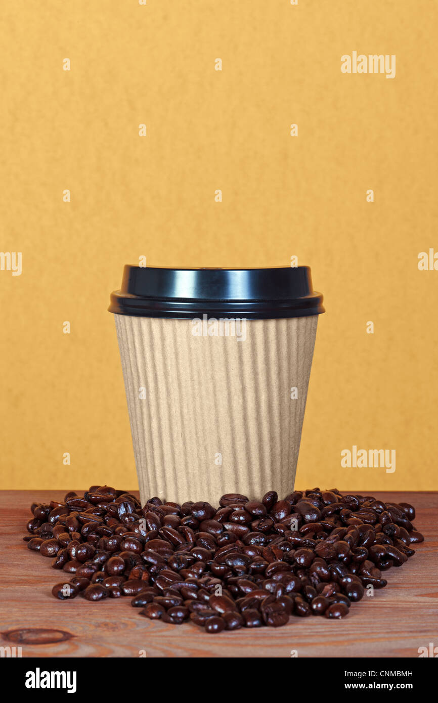 Photo of a takeway paper disposable cup with coffee beans and copy space to add you own message. Stock Photo
