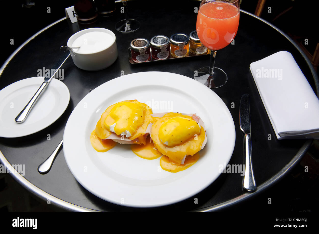 plate of eggs benedict two halves of English muffin topped with ham or bacon poached eggs and Hollandaise sauce breakfast brunch Stock Photo