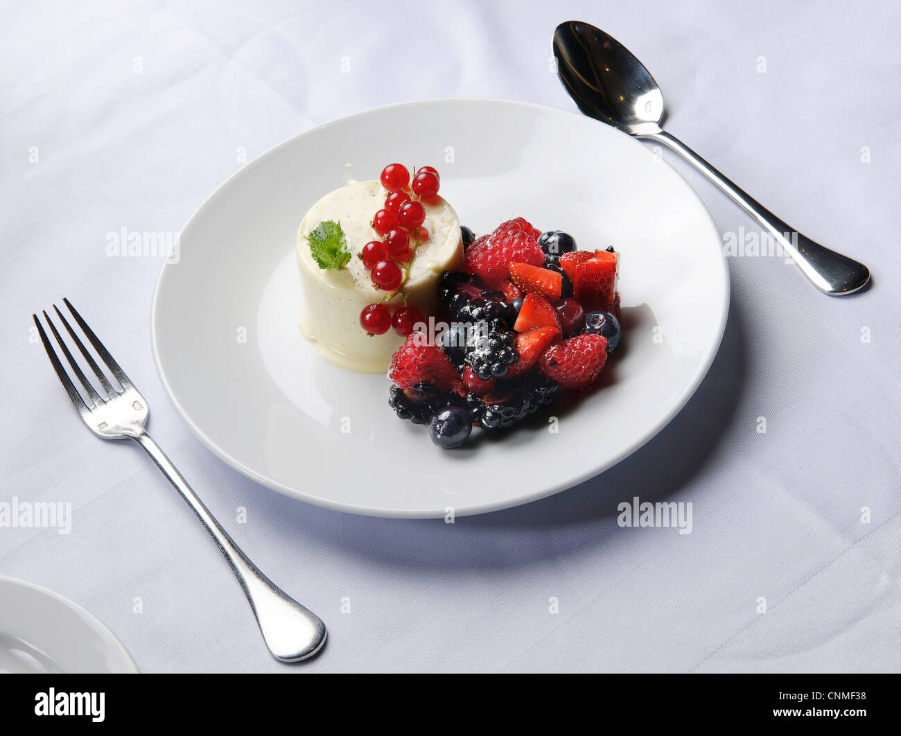 fruit pudding dessert blackberry, blueberry, raspberry red currants and strawberries on white tablecloth on restaurant table Stock Photo