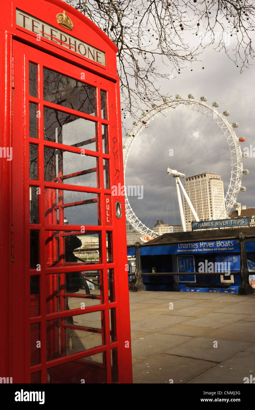 A red British telephone box with the London Eye in the background on
