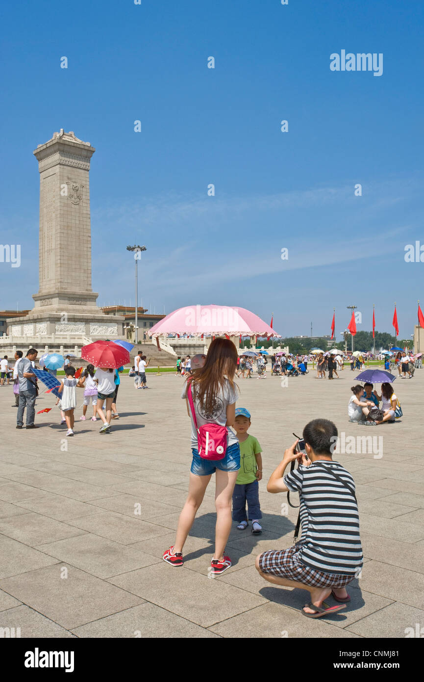Chinese tourists in Tiananmen Square taking photographs of each other with The Monument to the People's Heroes and The Great Hal Stock Photo