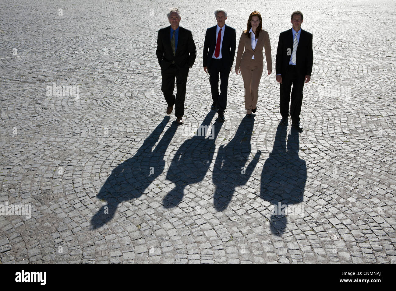 Business people walking on cobbled road Stock Photo