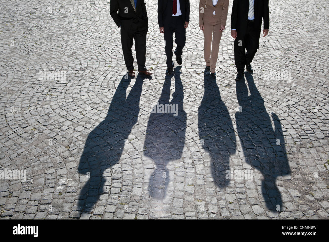 Shadows walking on cobbled road Stock Photo