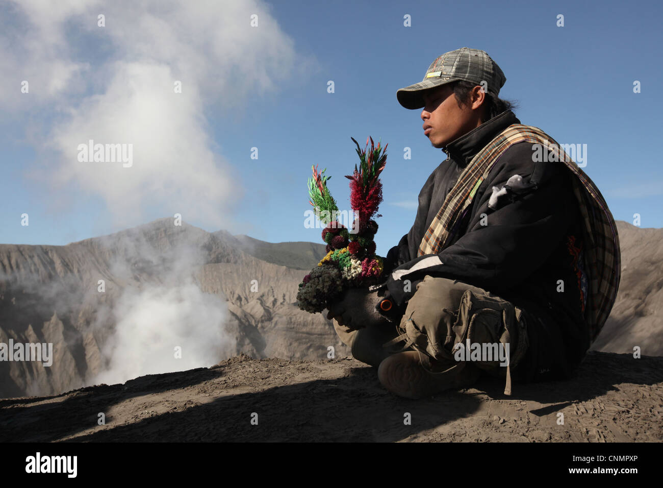 Young man of the Tenggerese sells flowers at the rim of the crater of Mount Bromo (2,329 m) in East Java, Indonesia. Stock Photo