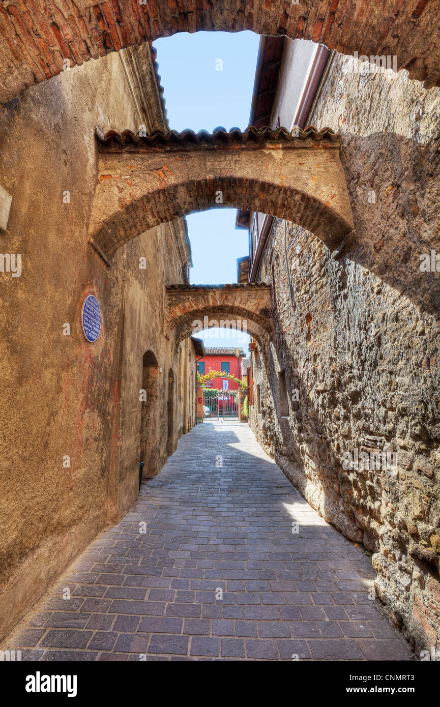 Vertical oriented image of arched pathway among ancient brick walls in Sirmione, Northern Italy. Stock Photo