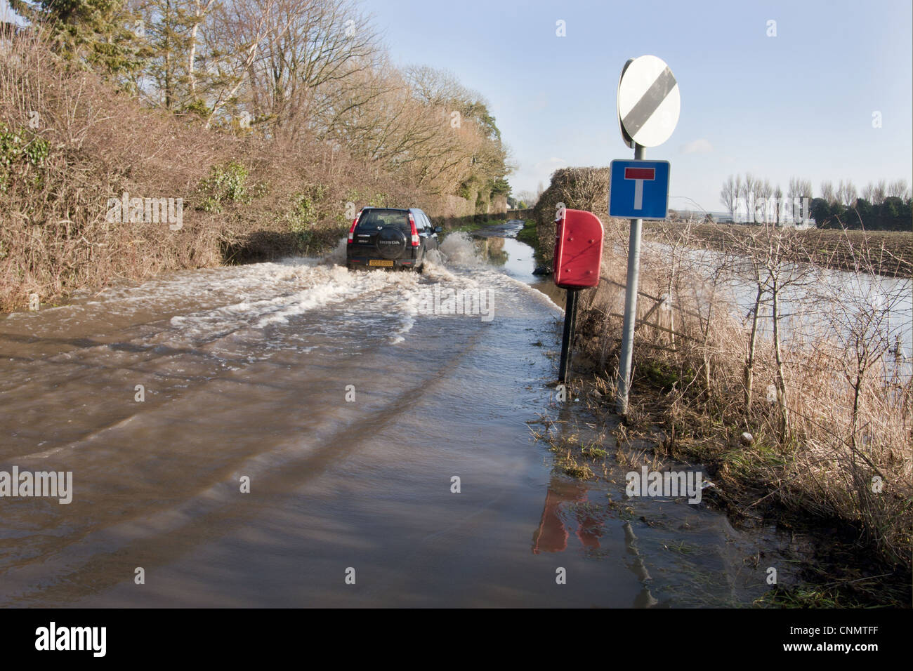 Flooded rural road with vehicle driving through, West Sussex, England, january Stock Photo
