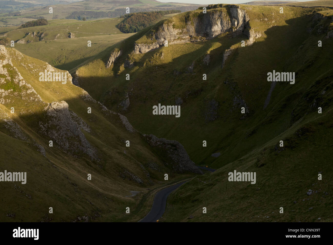 View of road through moorland with limestone pinnacles in shadow, Winnats Pass, Hope Valley, Peak District, Derbyshire, England Stock Photo