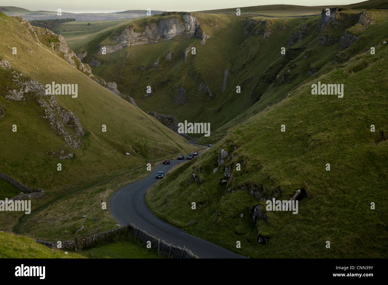 View of cars on road through moorland with limestone pinnacles, Winnats Pass, Hope Valley, Peak District, Derbyshire, England Stock Photo