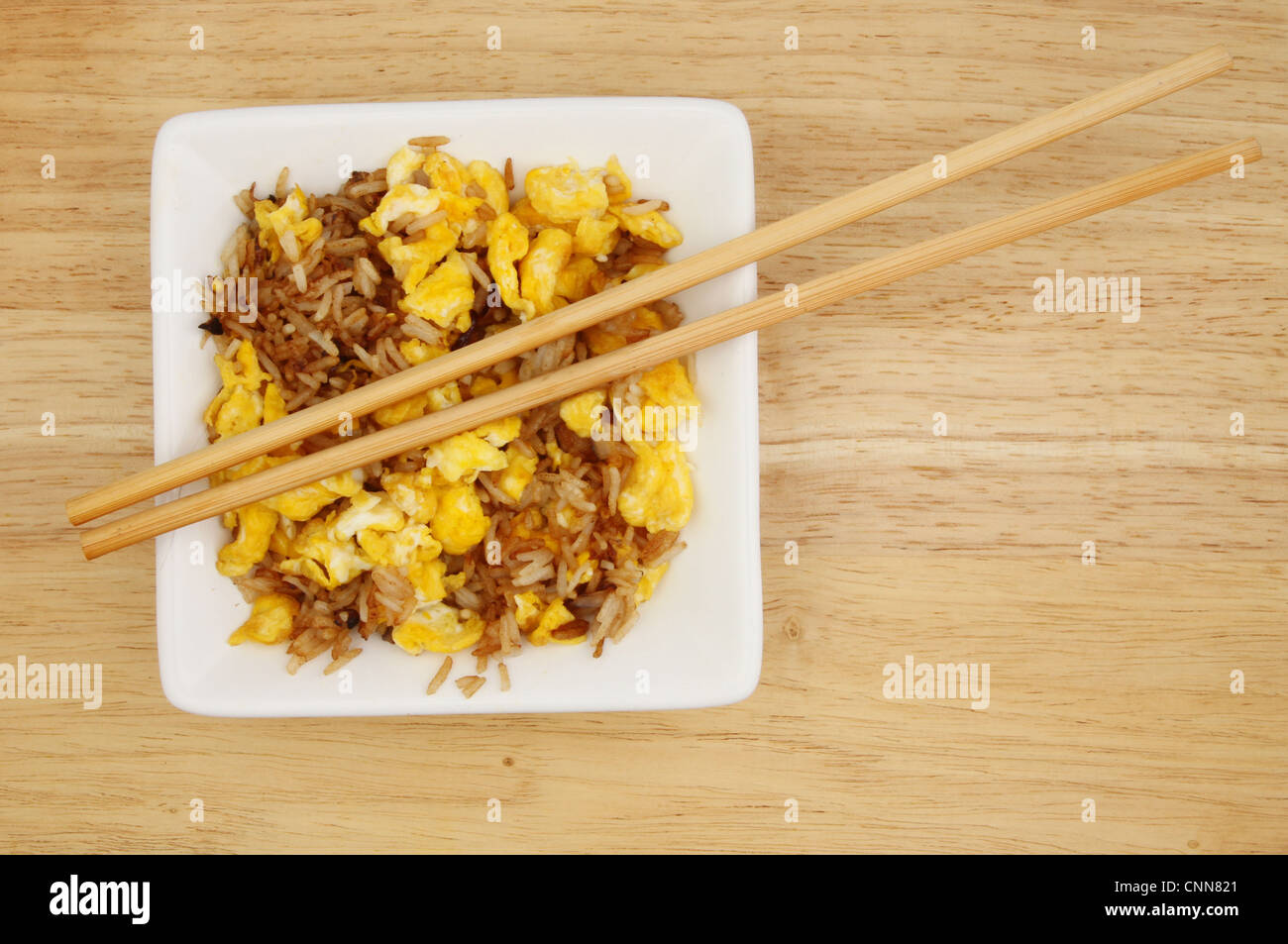 Egg fried rice in square bowl with chopsticks on a wooden surface Stock Photo