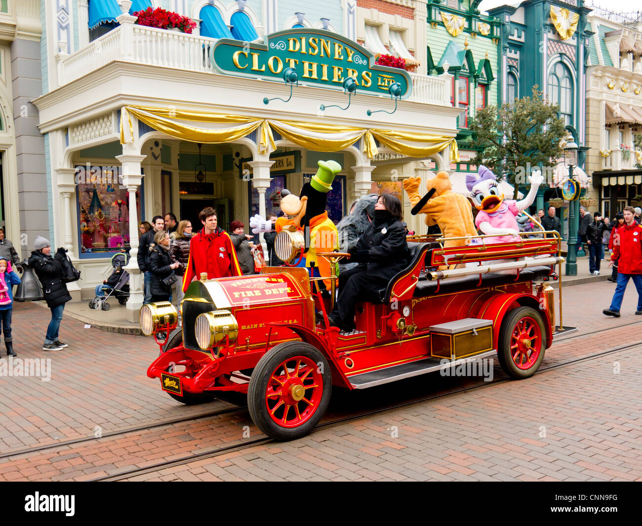 A fire truck at Disneyland Paris gives a ride to Goofy, Pluto and Daisy Duck Stock Photo